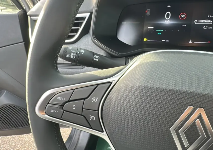 Gros plan sur le volant multifonctions cuir de la Renault Clio gris schiste, avec affichage numérique du tableau de bord.