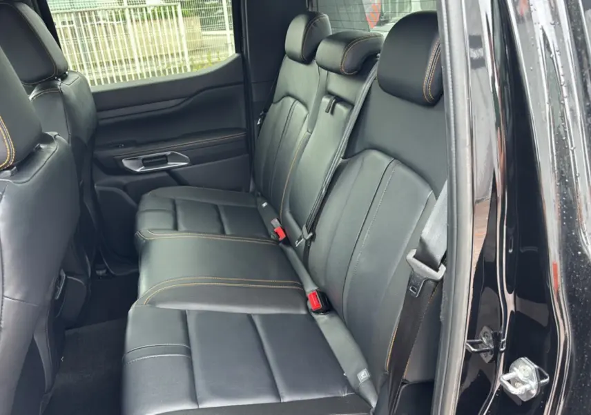 Vue intérieure côté droit sur les sièges arrière en cuir noir avec surpiqûres orange du Ford Ranger Wildtrak Plus 2025 noir agate.