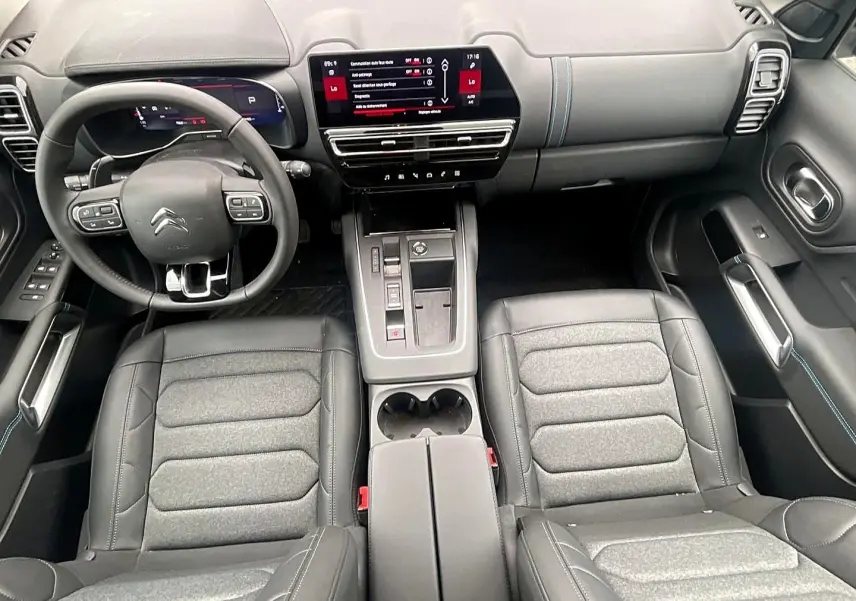 Vue intérieure avant du Citroën C5 Aircross 2025 noir, avec tableau de bord numérique et sièges en cuir gris.