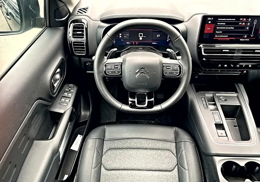 Vue intérieure centrée sur le volant et tableau de bord noir du Citroën C5 Aircross hybride 2025 avec écran tactile et commandes intégrées.
