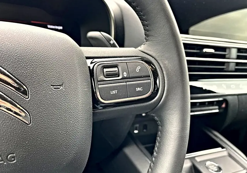 Gros plan sur le volant noir multifonction du Citroën C5 Aircross 2025, avec commandes audio et téléphone visibles.