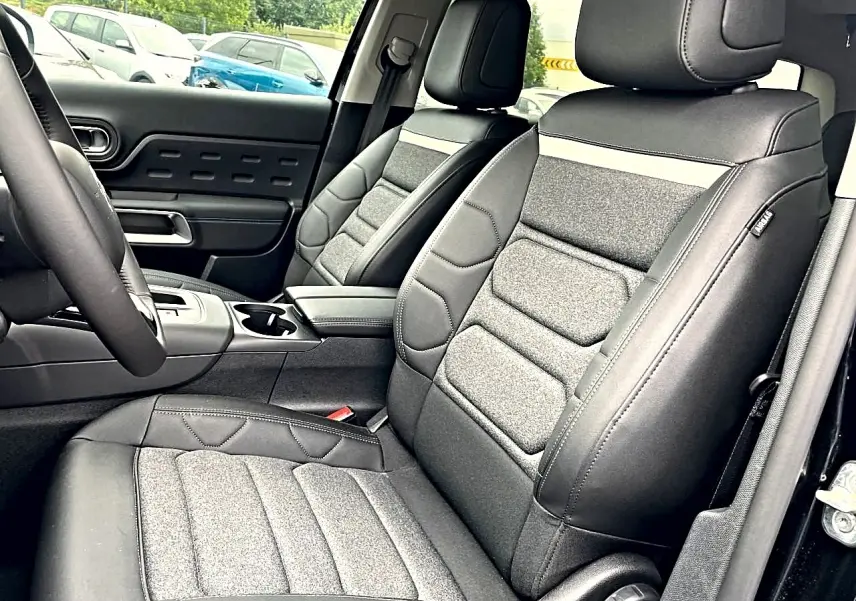 Vue intérieure côté avant droit du Citroën C5 Aircross 2025, sièges bi-matière gris et noir avec accoudoir central.