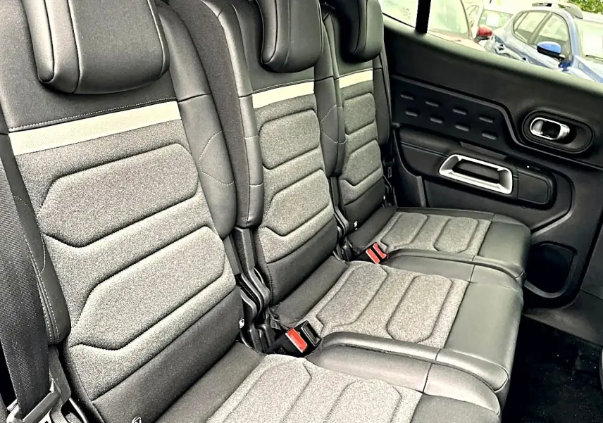 Vue latérale droite de la banquette arrière grise et noire du Citroën C5 Aircross avec appuie-têtes et ceintures visibles.
