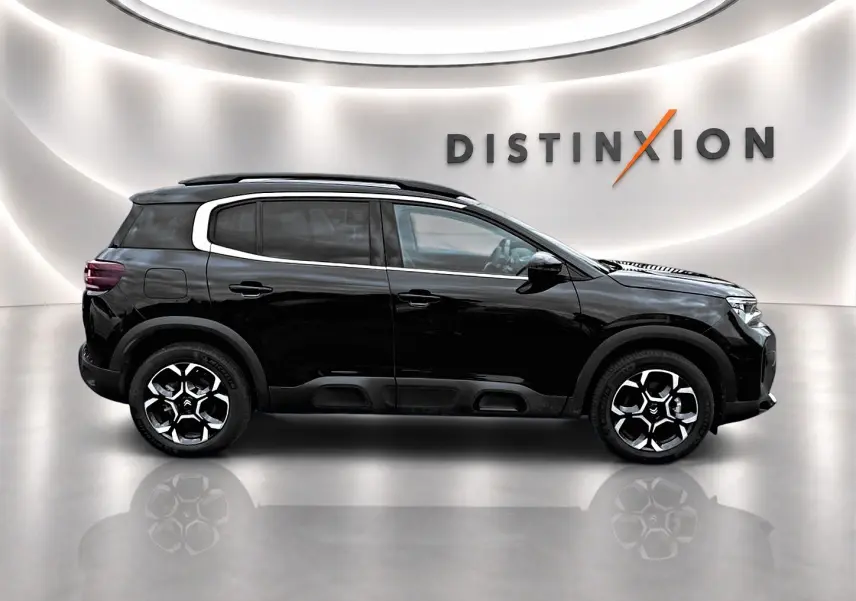 Profil droit du Citroën C5 Aircross noir 2025 avec jantes alu et toit noir dans un showroom lumineux.