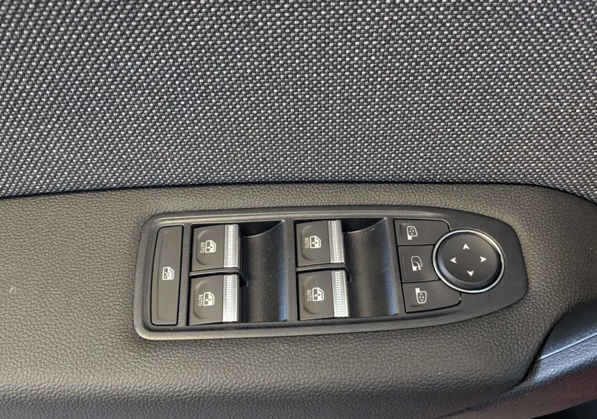 Panneau de commandes des vitres et rétroviseurs sur la porte côté conducteur d'un Renault Captur rouge flamme 2025.