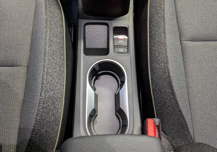 Gros plan sur la console centrale du Renault Captur E-Tech 2025, avec porte-gobelets et sièges gris à surpiqûres jaunes.