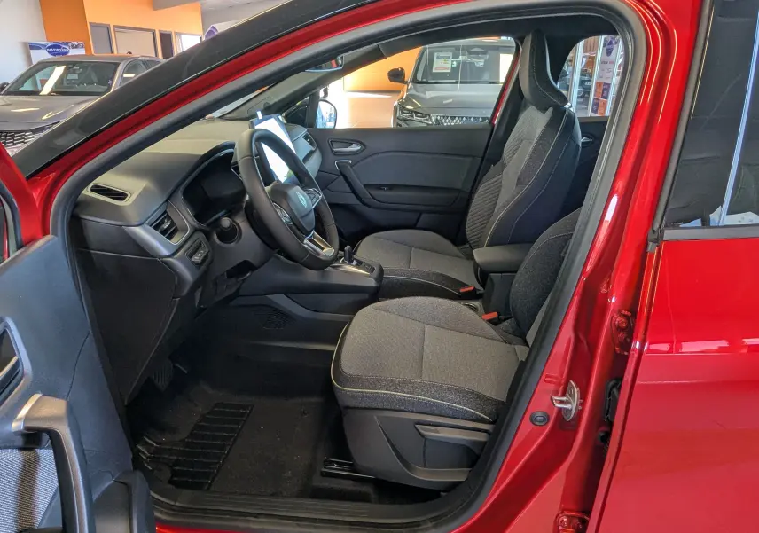 Intérieur côté conducteur du Renault Captur rouge flamme, montrant sièges gris et tableau de bord moderne.