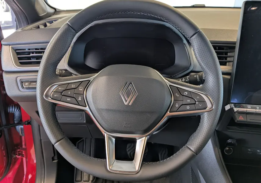 Vue rapprochée du volant cuir noir perforé du Renault Captur E-Tech 2025 avec commandes intégrées et tableau de bord digital éteint.