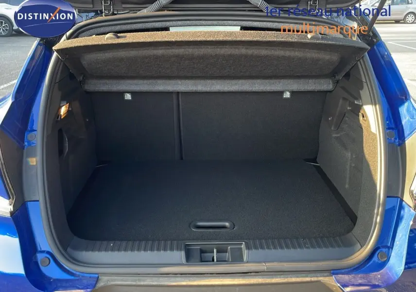 Coffre ouvert d'un Renault Captur E-Tech hybride 2025 bleu iron metal, vue arrière montrant l'espace de chargement vide.