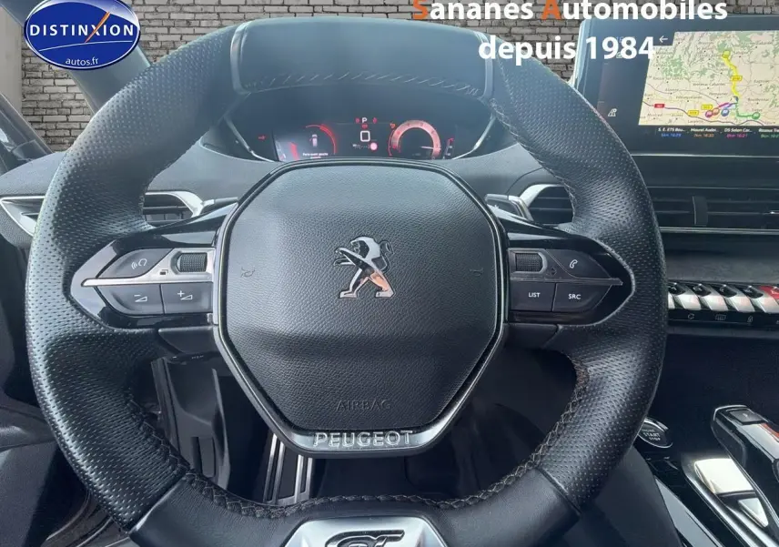 Vue rapprochée du volant cuir perforé avec badge GT et tableau de bord numérique du Peugeot 3008 gris foncé.