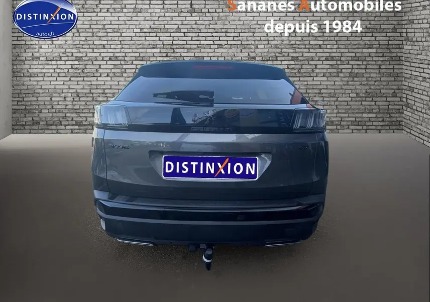 Vue arrière d’un Peugeot 3008 gris foncé avec attelage et bandeau noir brillant sur pare-chocs arrière.