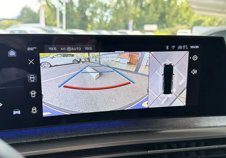 Écran central montrant la caméra de recul et vue 360° du Peugeot 1007 gris Artense en stationnement.