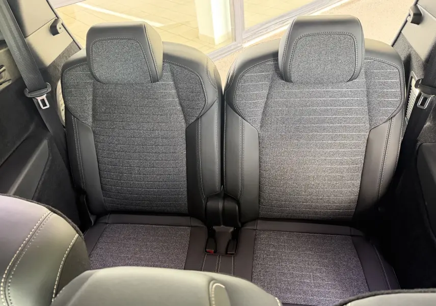 Vue rapprochée des sièges arrière en tissu gris et cuir noir du Peugeot 1007 Hybrid 145, finition Allure 2026.