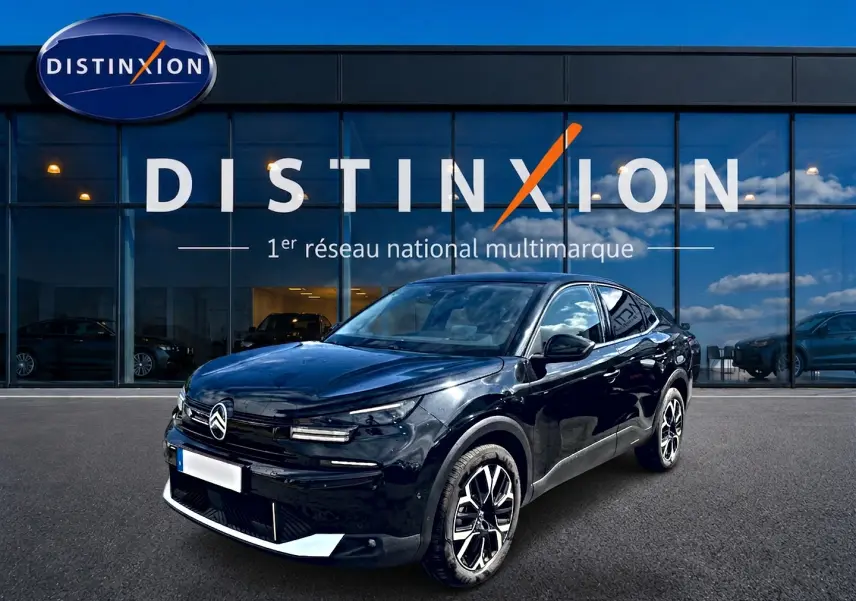 Citroën C4 X noir en 3/4 avant droit, avec jantes alu et calandre distinctive, devant une vitrine Distinxion.