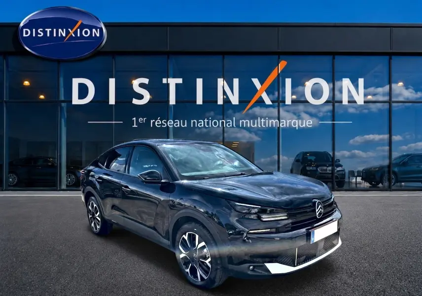 Citroën C4 X noir vue 3/4 avant droit, avec jantes alu distinctives, devant une vitrine Distinxion.