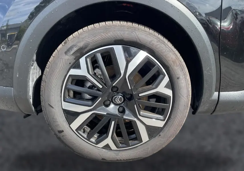 Gros plan sur la jante alu noire et argentée d'une Citroën C4 X noire, avec logo Citroën au centre.