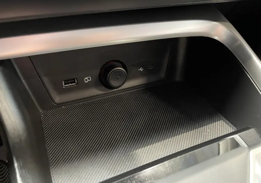 Gros plan sur la console centrale du MG ZS 1.5 Hybrid+ 2026, montrant les prises USB et la prise 12V dans un intérieur noir.