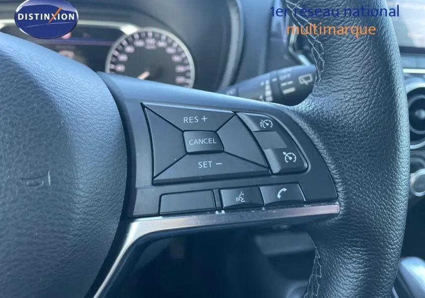 Gros plan sur les commandes au volant en cuir noir du Nissan Juke gris squale métal, version hybride 2024.