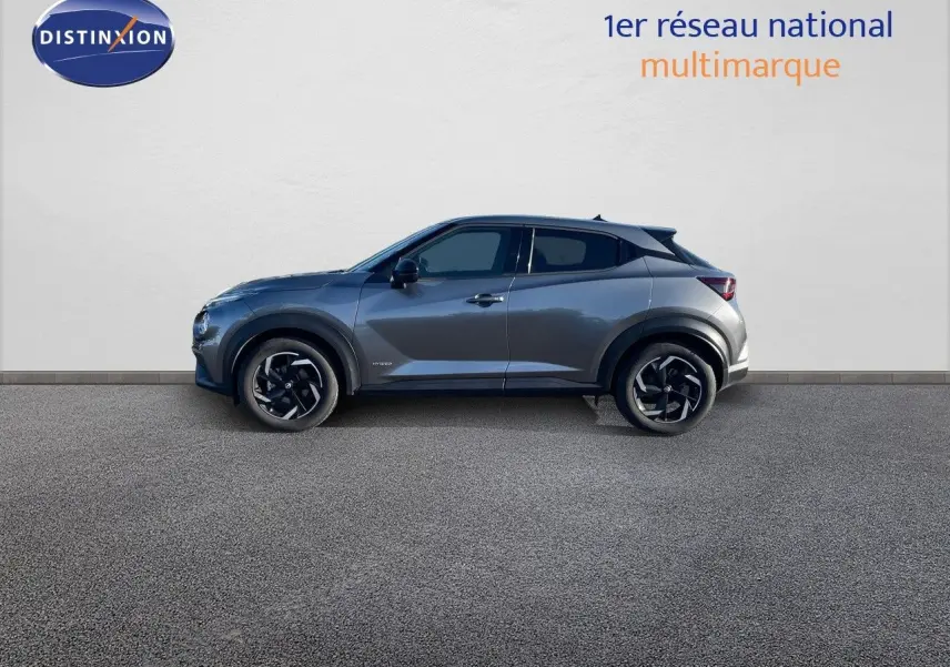 Profil côté gauche du Nissan Juke 1.6 HEV gris squale métal 2024, avec jantes noires et toit noir contrasté.