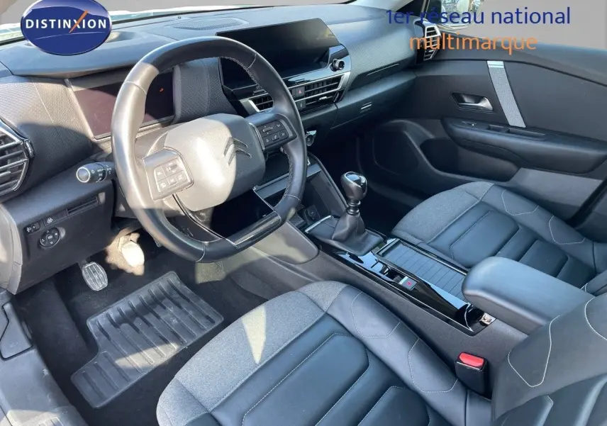 Intérieur de la Citroën C4 2021, vue côté conducteur, sièges bi-matière gris et tableau de bord moderne noir.