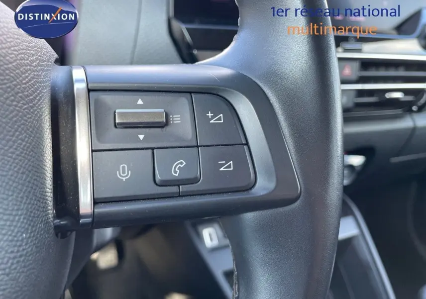 Gros plan sur les commandes au volant gauche d'une Citroën C4 2021 bleu Iceland Metal, intérieur moderne et épuré.