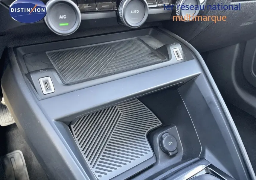 Vue rapprochée de la console centrale noire du Citroën C4 2021 avec commandes climatisation et prise 12V visible.