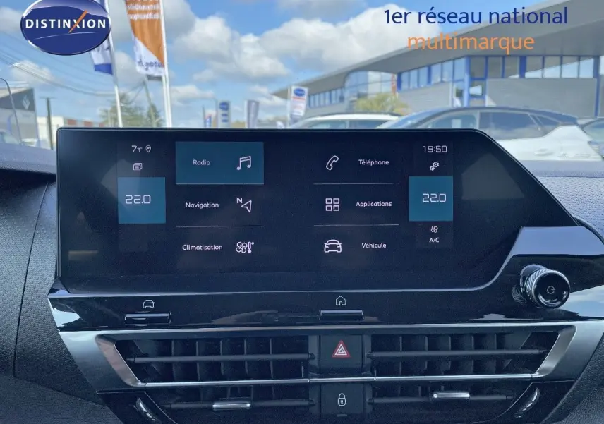 Vue rapprochée de l'écran tactile central du tableau de bord d'une Citroën C4 bleu Iceland Metal, affichant les options multimédia et climatisation.