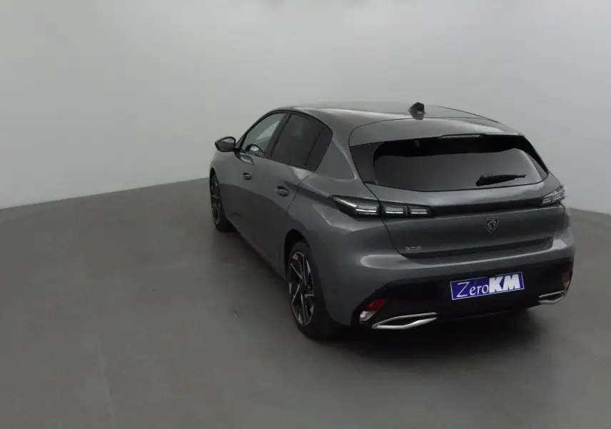 Peugeot 308 gris selenium vue 3/4 arrière droit dans un studio, avec feux arrière LED et double sortie d’échappement chromée.