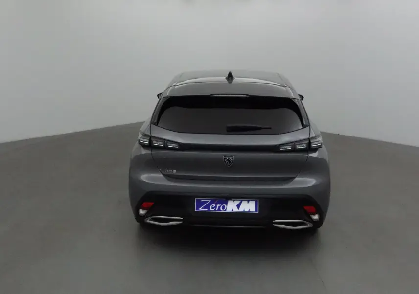 Vue arrière d'une Peugeot 308 gris selenium avec feux LED et double sortie d'échappement chromée dans un studio.
