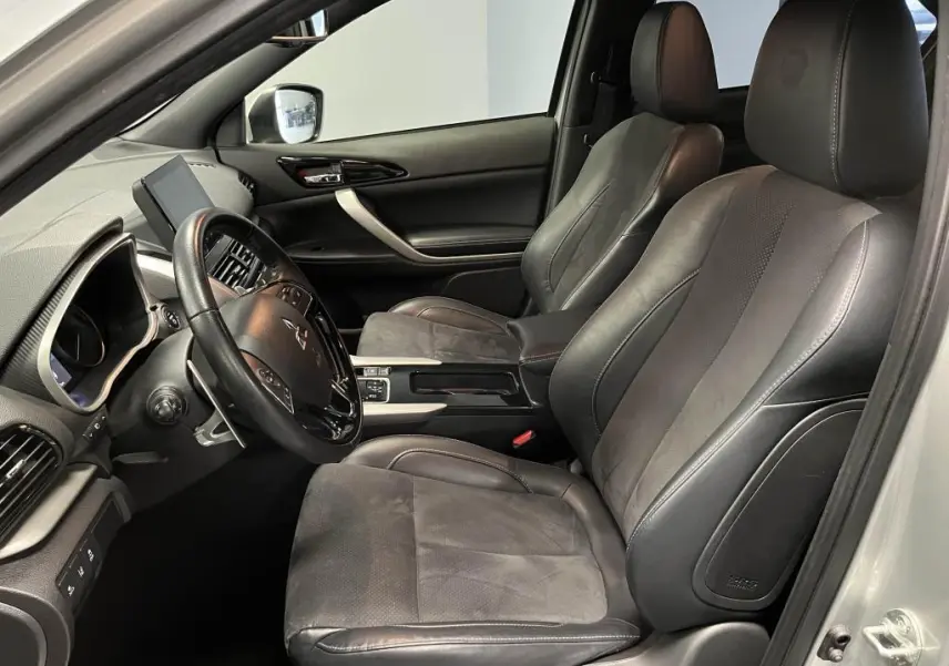 Intérieur avant du Mitsubishi Eclipse Cross gris, sièges en cuir noir et suédine, volant multifonction et écran tactile visible.