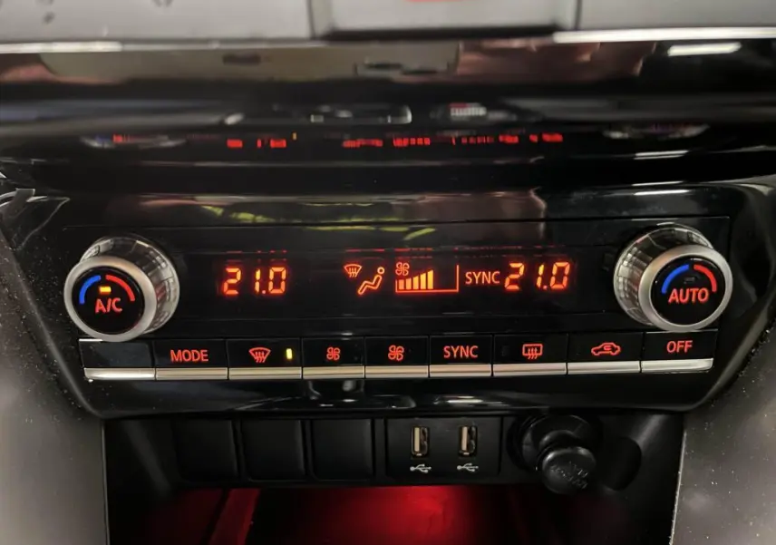 Panneau de climatisation automatique bi-zone rouge éclairé du Mitsubishi Eclipse Cross gris, avec commandes et prises USB visibles.