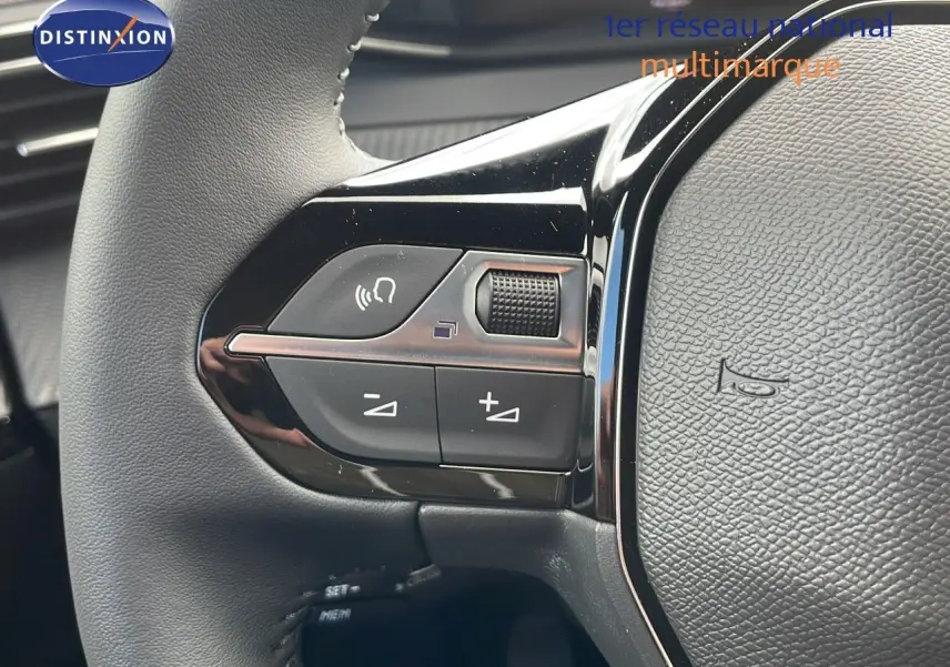 Gros plan sur les commandes gauche du volant du Peugeot 2008 bleu Vertigo Metal, montrant les boutons de volume et appel.
