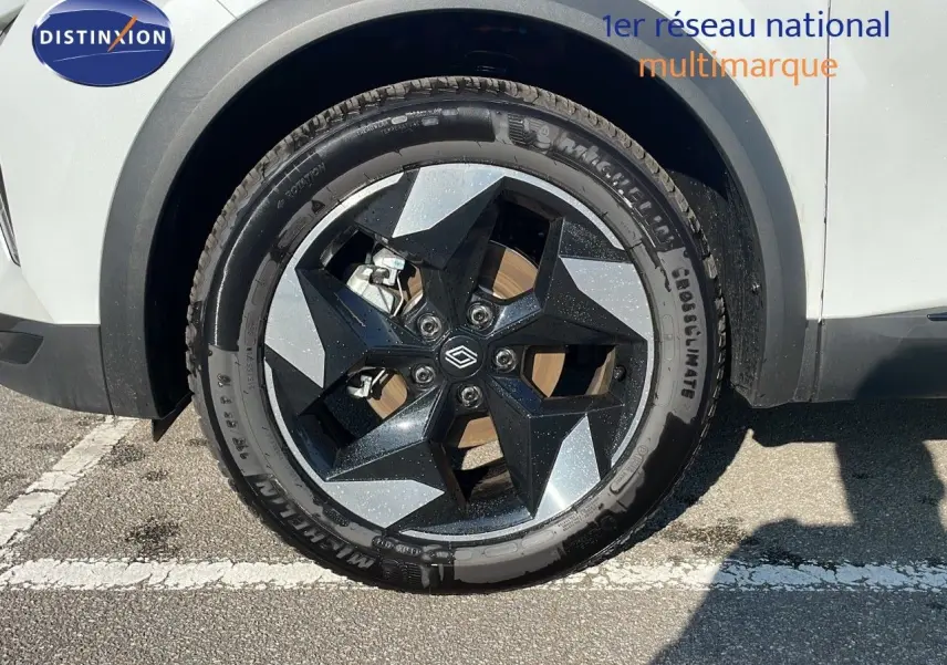 Gros plan sur la roue avant gauche du Renault Captur blanc nacré avec jante bi-ton noire et grise.