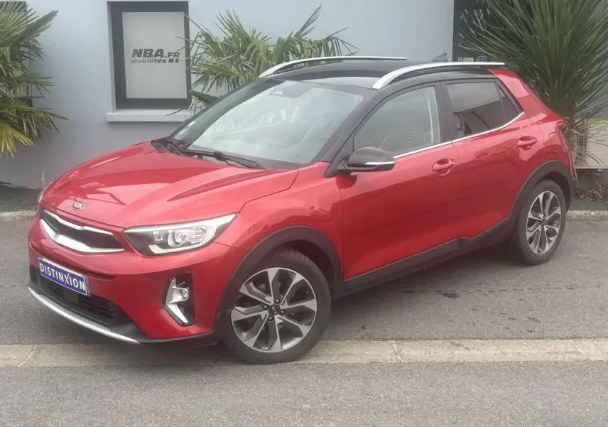 KIA Stonic rouge métallisé vue 3/4 avant droit avec jantes alliage et toit ouvrant panoramique.