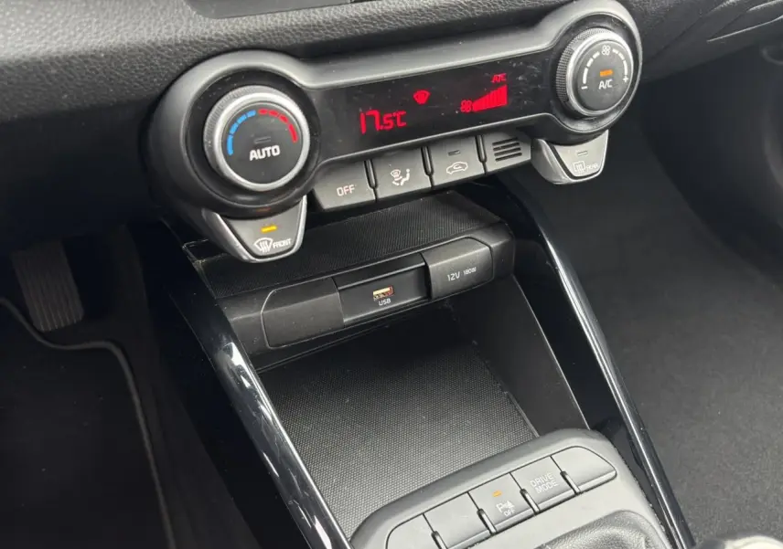 Vue rapprochée de la console centrale noire du Kia Stonic rouge, avec commandes climatisation et ports USB visibles.