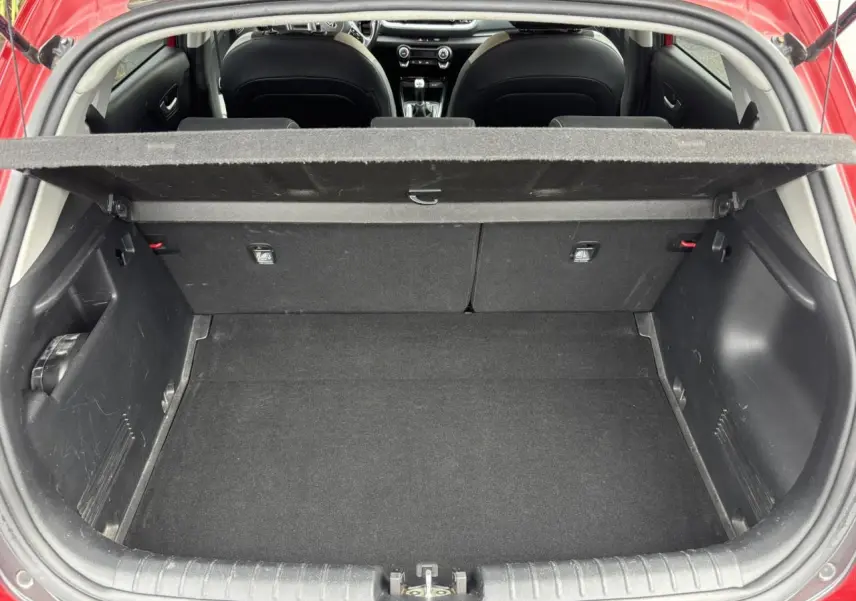 Coffre ouvert vu de l'arrière d'un KIA Stonic rouge, montrant l'espace de chargement et l'intérieur noir.