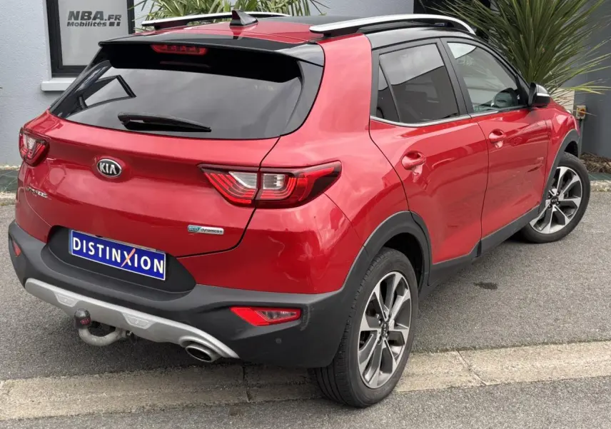 Vue 3/4 arrière droite d'un Kia Stonic rouge métallisé avec attelage et jantes alliage 17 pouces.