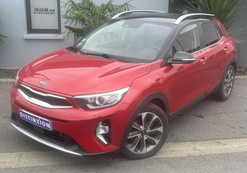 KIA Stonic rouge métallisé vue 3/4 avant droit avec toit noir et jantes alliage 17 pouces.
