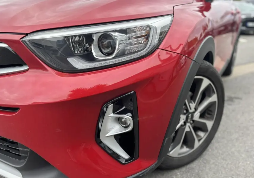 Gros plan sur l'avant droit rouge métallisé du KIA STONIC 2020, mettant en valeur le phare et le projecteur antibrouillard.