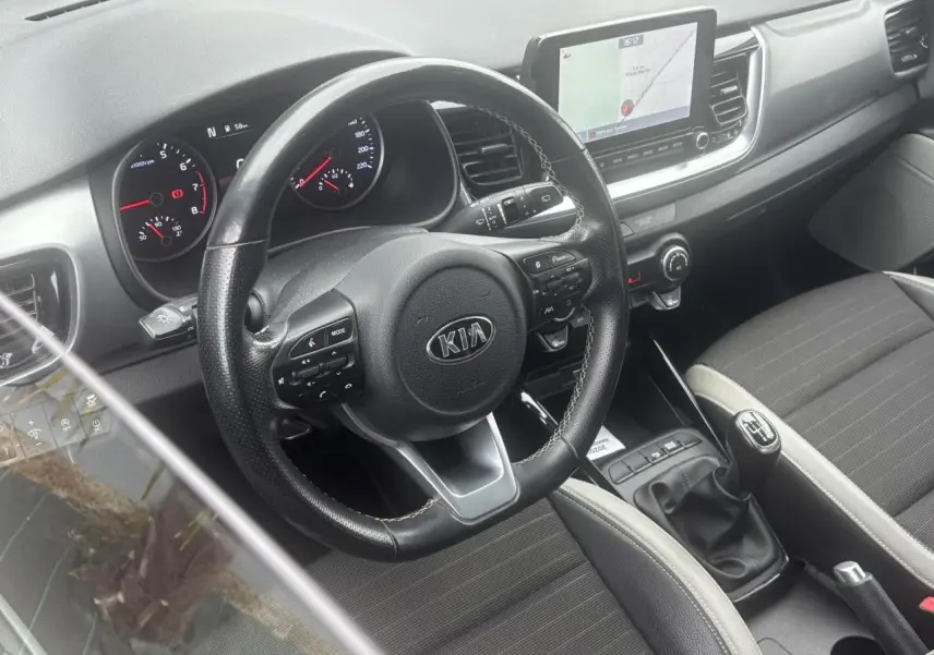 Vue intérieure côté conducteur du tableau de bord et volant KIA Stonic avec écran tactile et levier de vitesses manuel.
