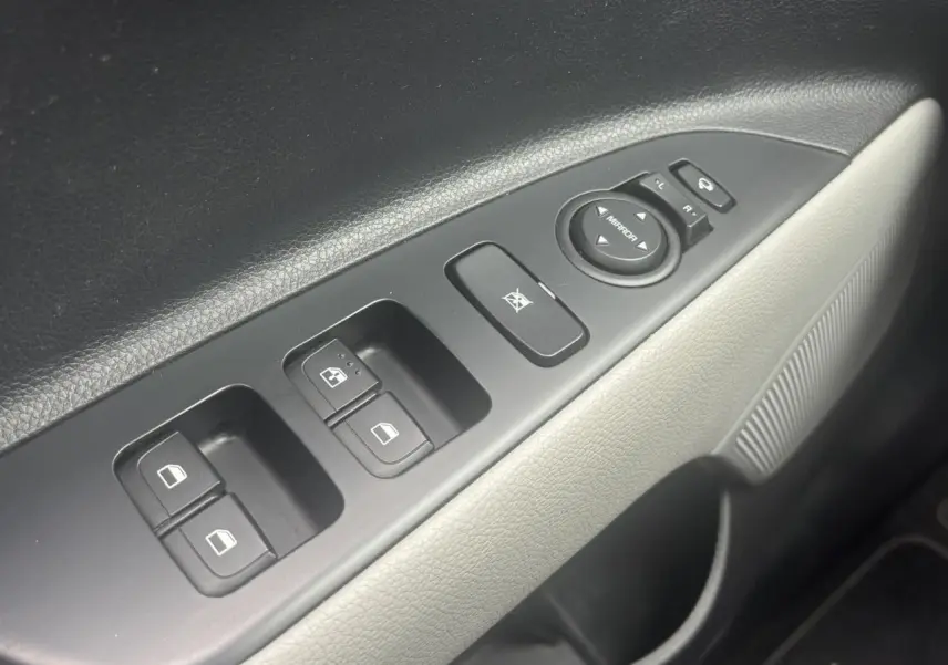 Gros plan sur la commande des vitres électriques côté conducteur du Kia Stonic rouge, avec réglage des rétroviseurs.