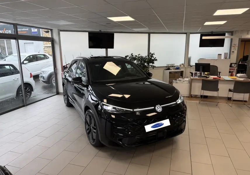 Volkswagen T-Roc Noir Intense en vue 3/4 avant droit dans un showroom avec jantes noires et calandre R-Line.