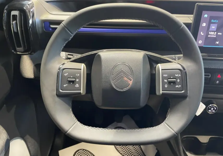 Vue rapprochée du volant cuir noir de la Citroën C3 2025 avec commandes intégrées et tableau de bord moderne.