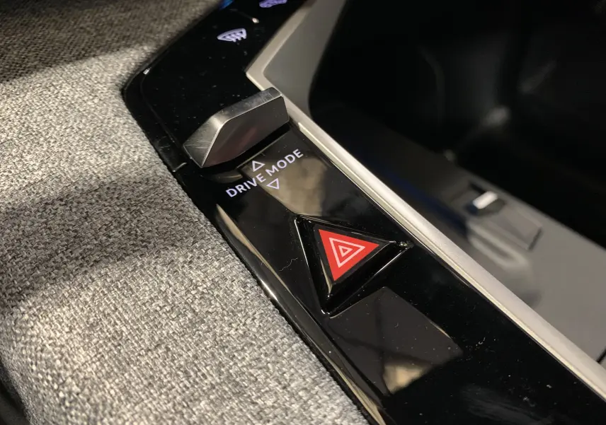Gros plan sur la console centrale du Peugeot 3008 III GT Hybrid 136 e-DSC6, avec bouton Drive Mode et signal d’alerte rouge.