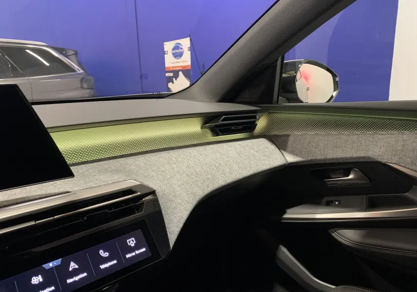 Intérieur avant droit du Peugeot 3008 III GT Hybrid 136 e-DSC6 2025 avec tableau de bord gris clair et éclairage d'ambiance vert pâle.