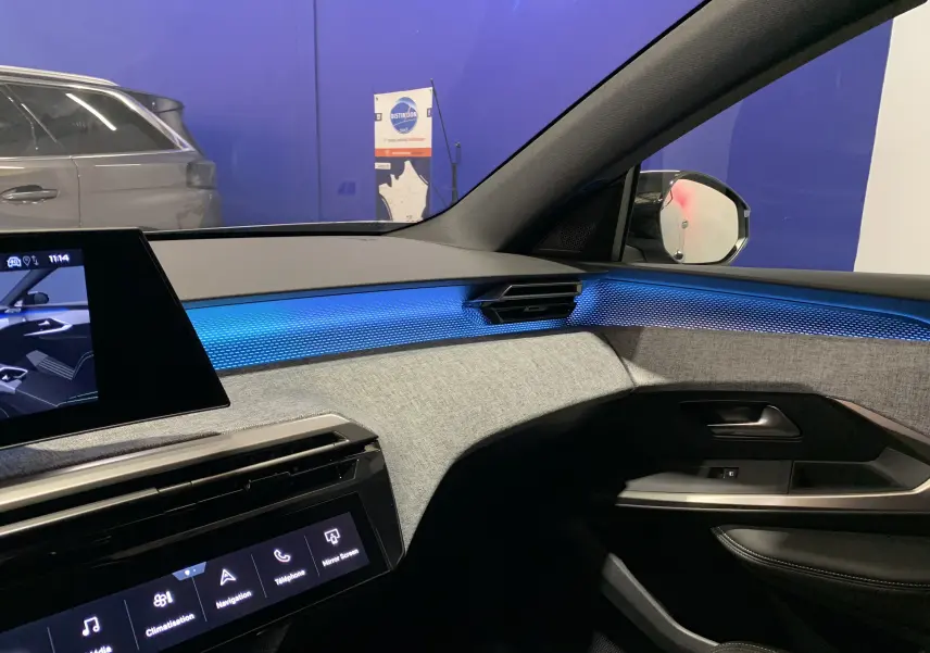 Intérieur du Peugeot 3008 III GT Hybrid 136 e-DSC6 2025, vue côté passager avec éclairage d'ambiance bleu et finition tissu gris.