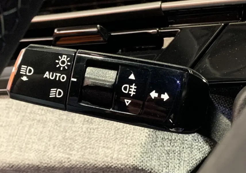 Gros plan sur la commande des feux et clignotants du Peugeot 3008 III GT Hybrid 136 e-DSC6, intérieur noir.