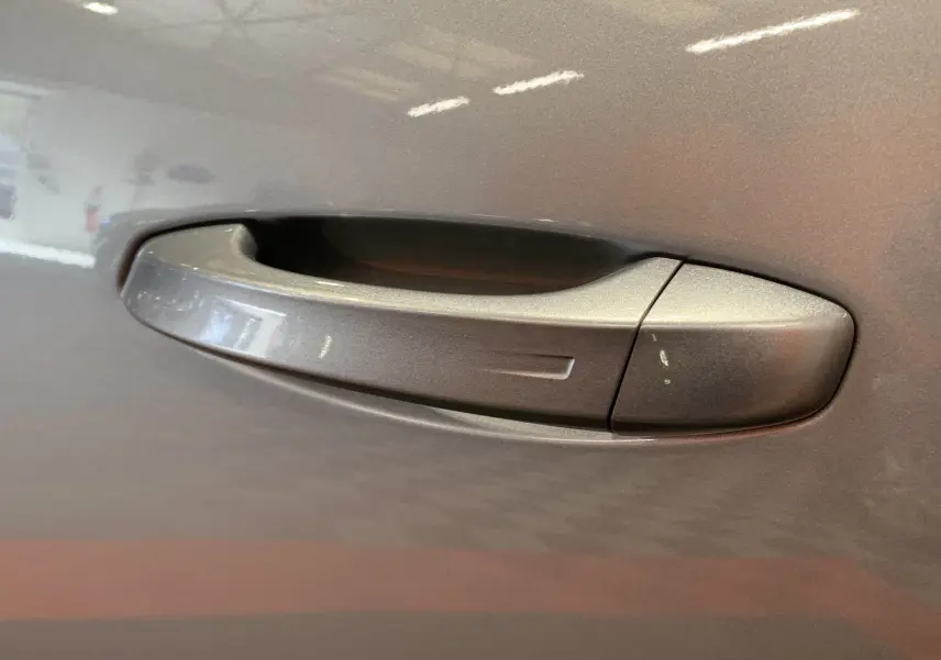 Poignée de porte gris Artense du côté gauche du Peugeot 3008 III GT HYBRID 136 e-DSC6 2025 en gros plan.