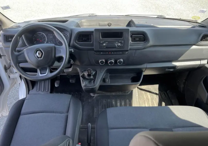 Intérieur du Renault Master 2020 vue de face, tableau de bord noir avec volant, levier de vitesses manuel et sièges tissu carbone.