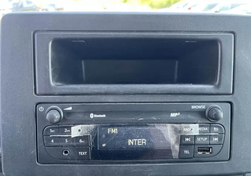 Radio d'origine avec écran FM et commandes intégrées sur le tableau de bord noir du Renault Master blanc.